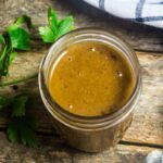 Homemade enchilada sauce in a mason jar with fresh herbs and a linen around the jar.