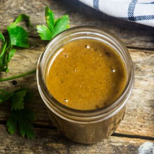 Homemade enchilada sauce in a mason jar with fresh herbs and a linen around the jar.