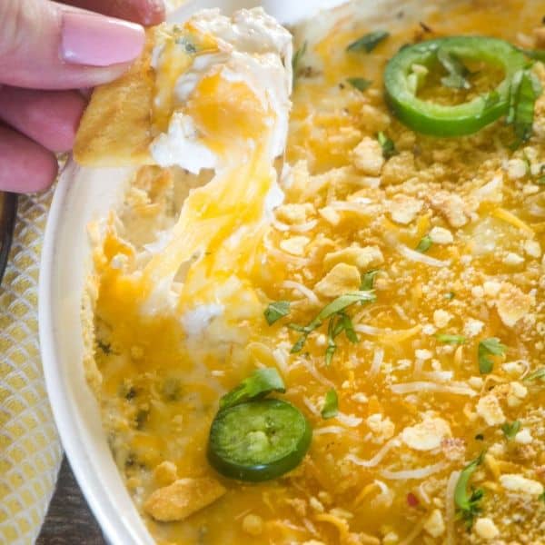 a cracker being pulled out of jalapeno popper dip with cheese and dip!