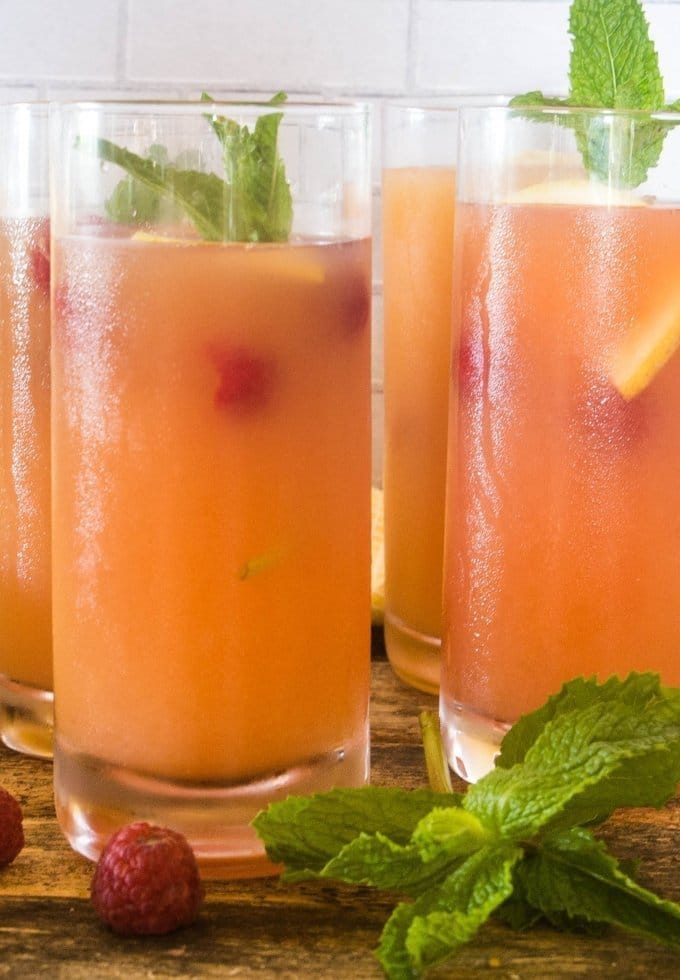 Refreshing summer punch in tall glasses garnished with fresh fruit and mint.