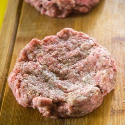 Seasoned ground beef formed into patties ready to be grilled.