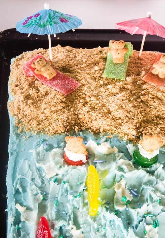 Festive beach cake topped with teddy grahams, tiki umbrellas