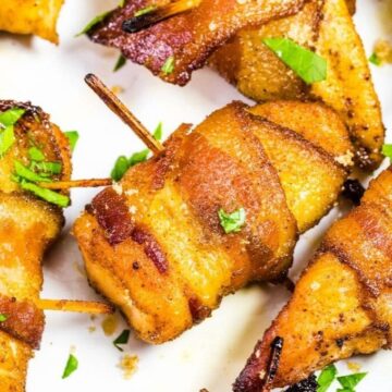 Chicken pieces wrapped with bacon on a white platter