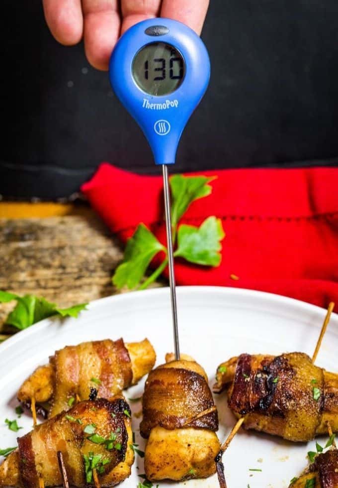 A piece of chicken with a digital thermometer to check the internal temperature of chicken.