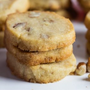 Crispy pecan cookies stacked on a cookie tray.