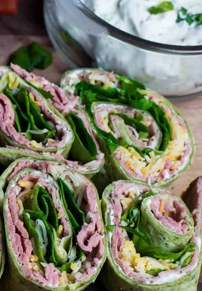 four tortilla rollups with a bowl of whipped cheese seasoned dip.