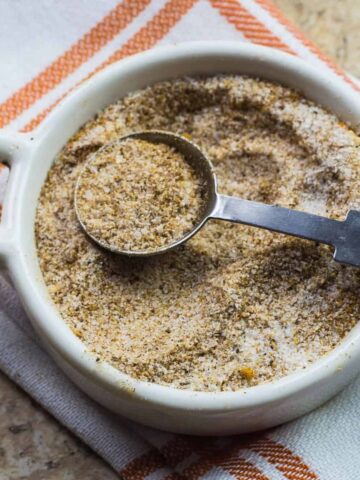 homemade seasoning salt in a white plate with a measuring spoon on the plate.