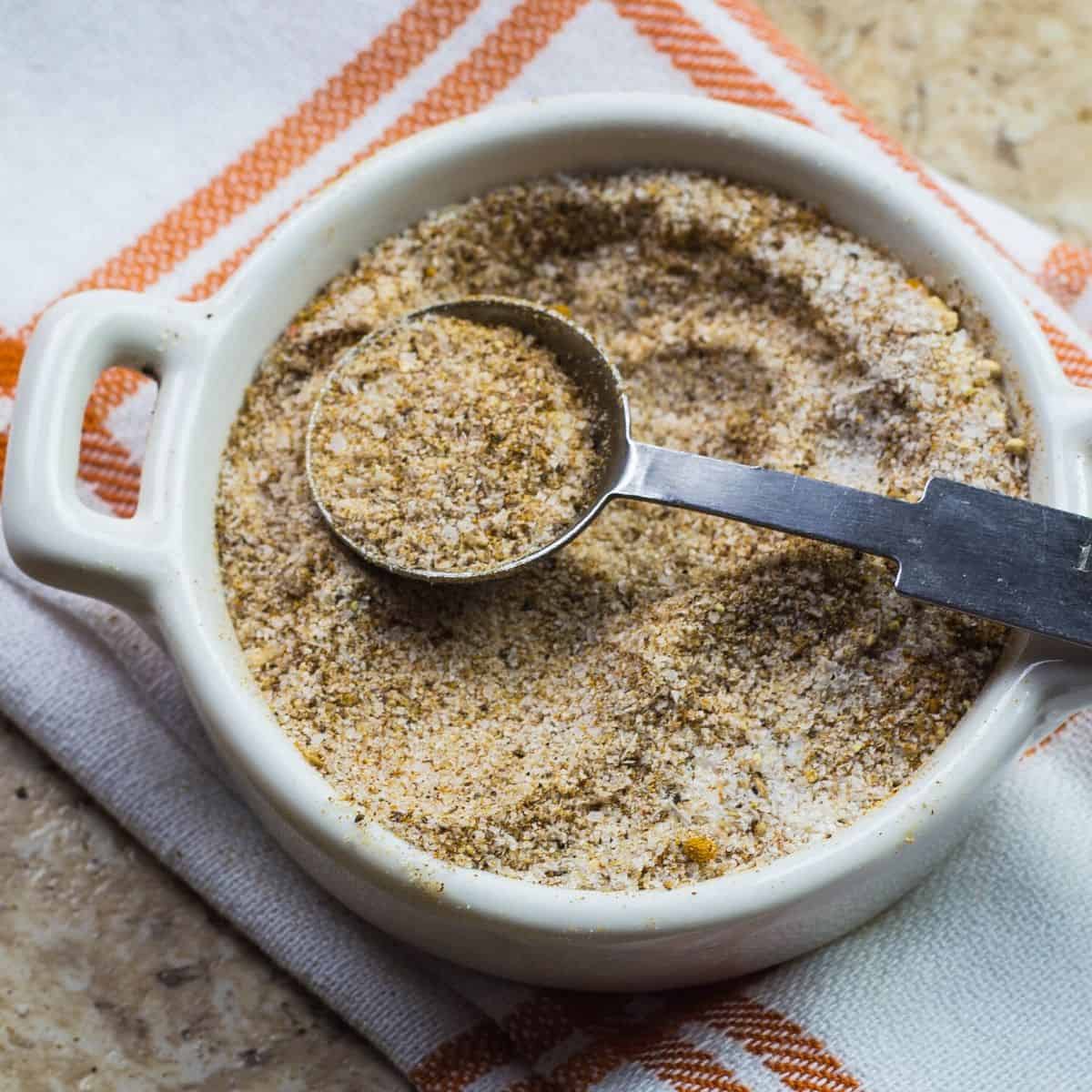 homemade seasoning salt in a white plate with a measuring spoon on the plate.