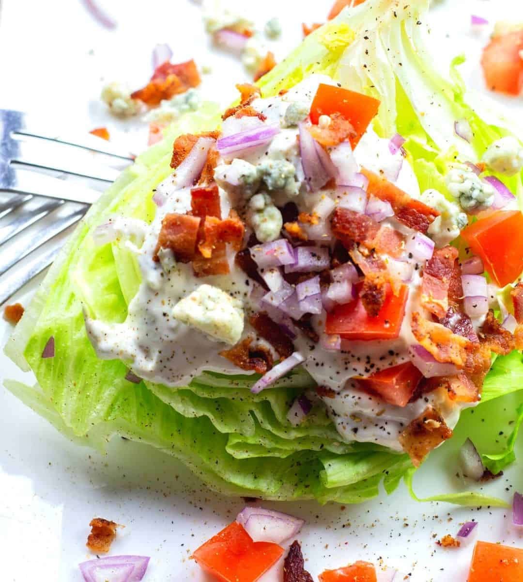 A delicious iceberg lettuce salad topped with bacon, tomatoes and blue cheese.