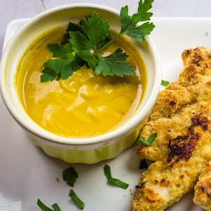 homemade honey mustard sauce with fresh parsley in a yellow bowl.