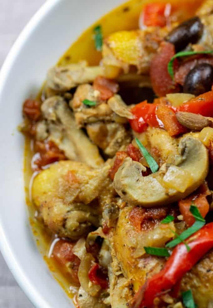 Chicken, mushrooms and peppers in a tomato sauce in a white bowl