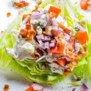 A classic wedge salad loaded with bacon. tomatoes, onion, and fresh blue cheese.