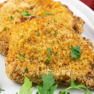 Crispy pork chops with a bread crumb coating on a white plate