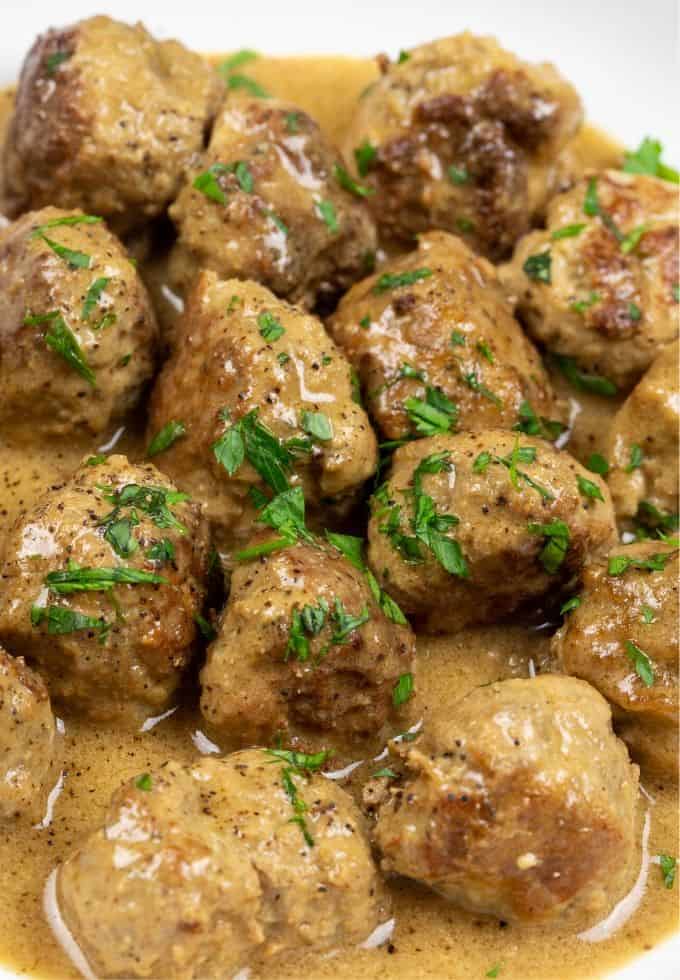 Homemade Swedish meatball in a brown creamy gravy sitting in a white bowl.