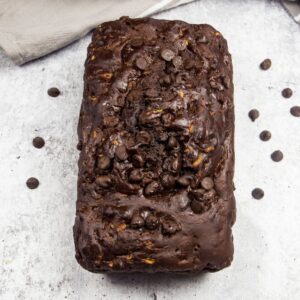 A loaf of double chocolate zucchini bread on a tray sprinkled with chocolate chips