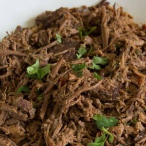 A bowl of shredded beef topped with chopped cilantro for tacos