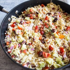 A large black pan holding a batch of Greek orzo pasta salad recipe