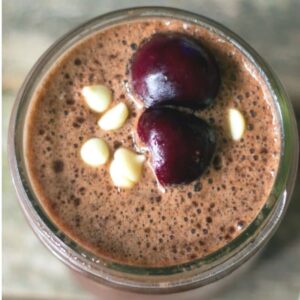 An overhead view of a chocolate smoothie topped with diced cherries.