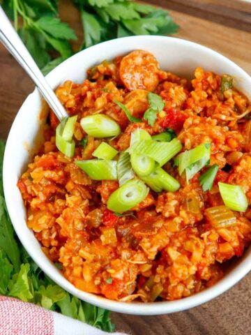 An overhead shot of cauliflower rice and a cajun based sauce topped with green onions
