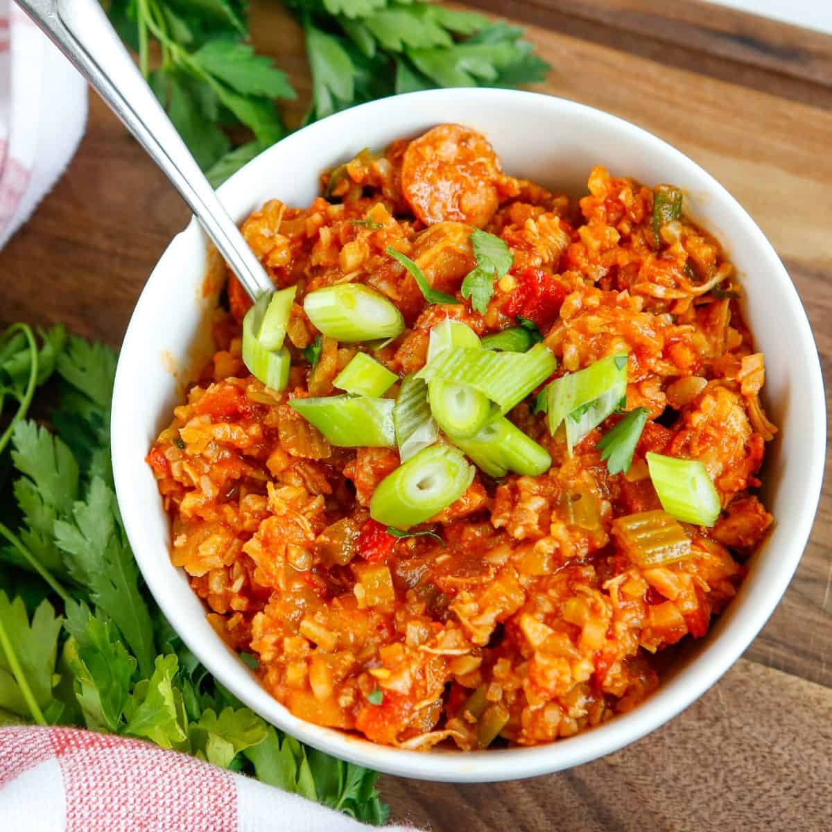 An overhead shot of cauliflower rice and a cajun based sauce topped with green onions