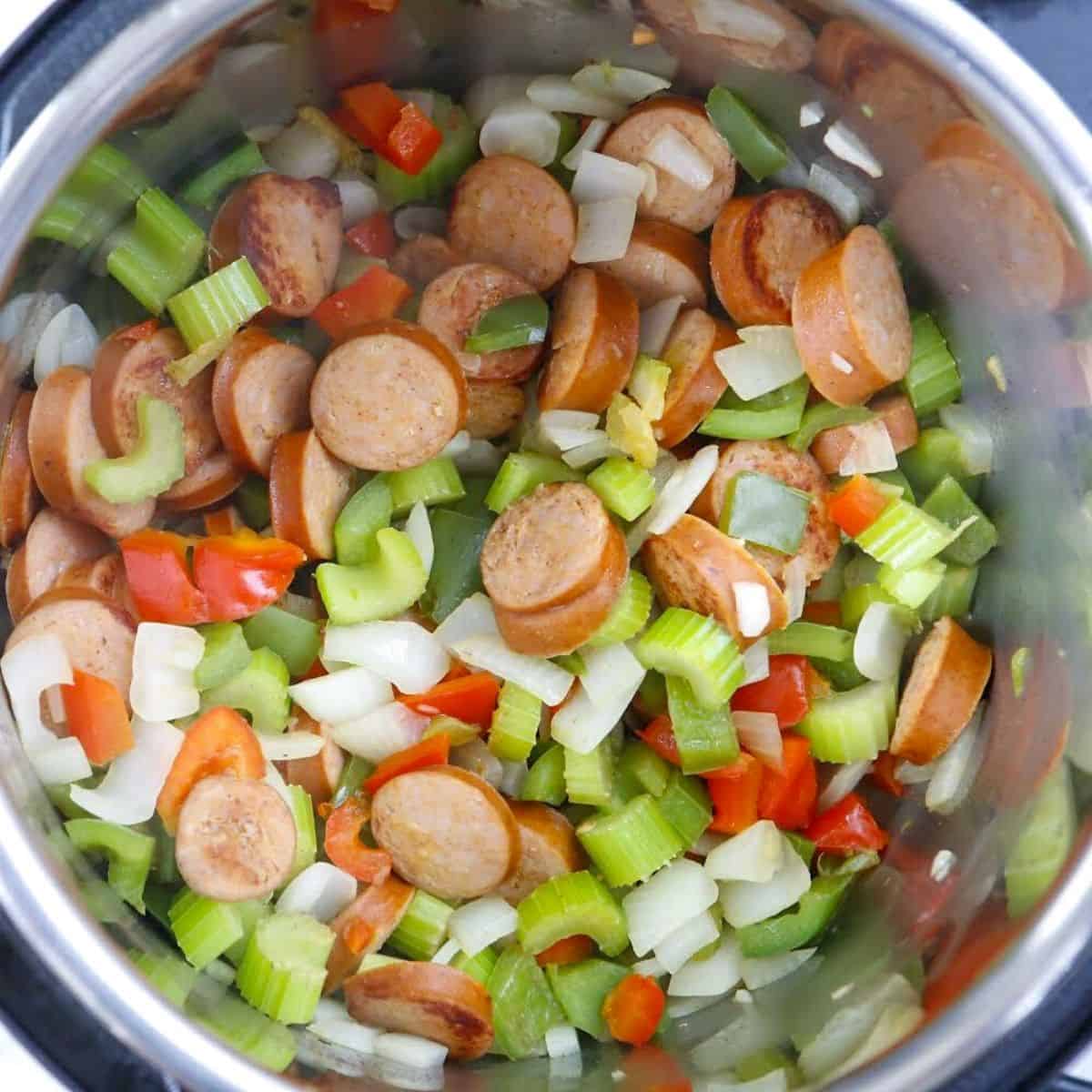 Celery, onions, celery, and sausage browning in a dutch oven to make jambalaya