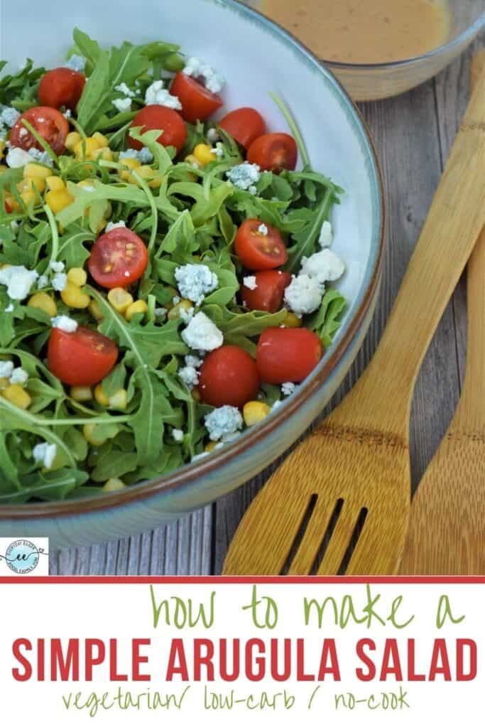 an arugula salad in a bowl with wooden serving spoons on the side