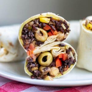 A veggie wrap filled with black rice, olives, tomatoes, and corn.