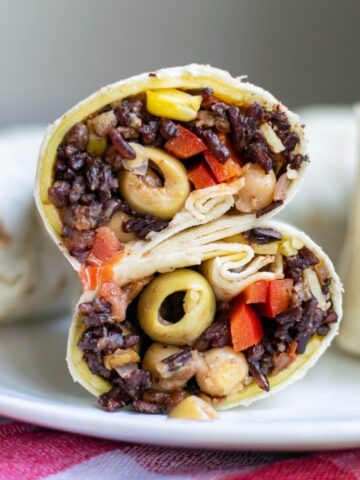 A veggie wrap filled with black rice, olives, tomatoes, and corn.