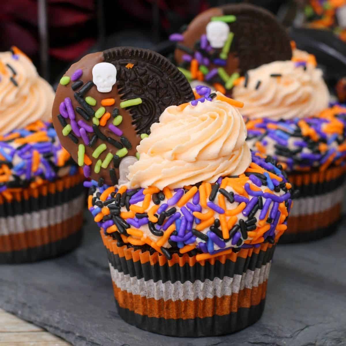 Cupcakes with a halloween theme with orange and purple sprinkles.