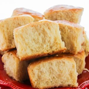 A stack of fluffy Hawaiian rolls on a red plate.