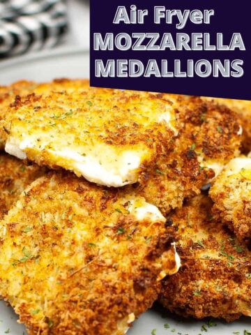 Panko encrusted mozzarella slices on a grey plate with herbs sprinkled around the plate.