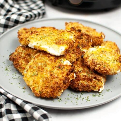 Sliced mozzarella coated with Panko bread crumbs on a grey plate.