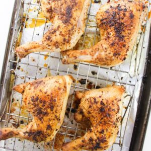 chicken leg quarters that have been roasted on a baking tray.