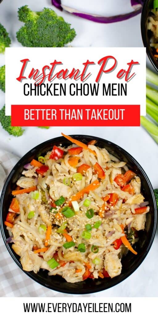 An overhead shot of chicken , noodles, and veggies in a black bowl.