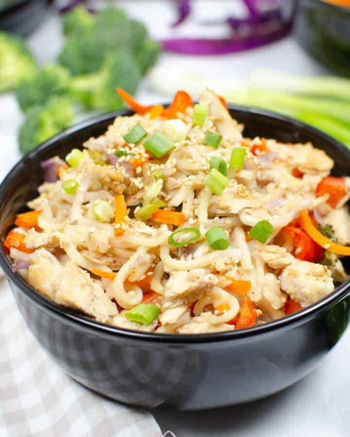 Chow mein noodles, veggies, and chicken in a bowl topped with green onions.