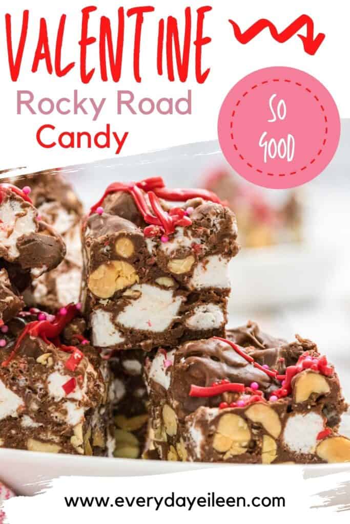 A plate stacked with rocky road candy squares topped with red drizzled icing on it.