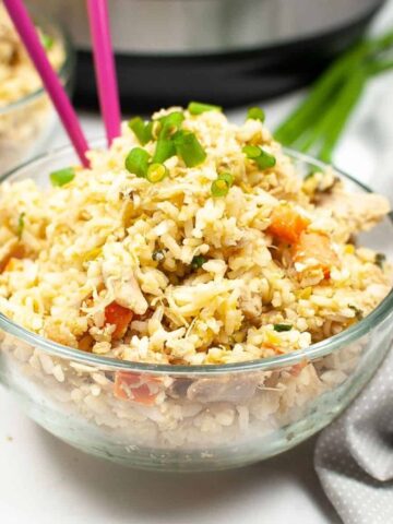 A bowl of rice and shredded chicken with pink chopsticks in the rice.