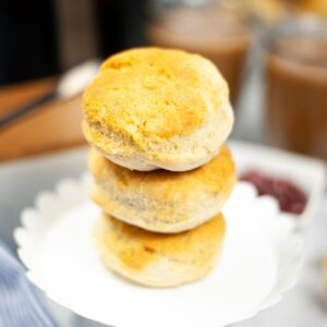 Homemade biscuits stacked up on a white cake stand.