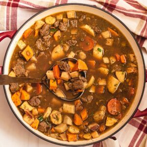 A large Braiser pot filled with veggies and beef in a dark brown broth.
