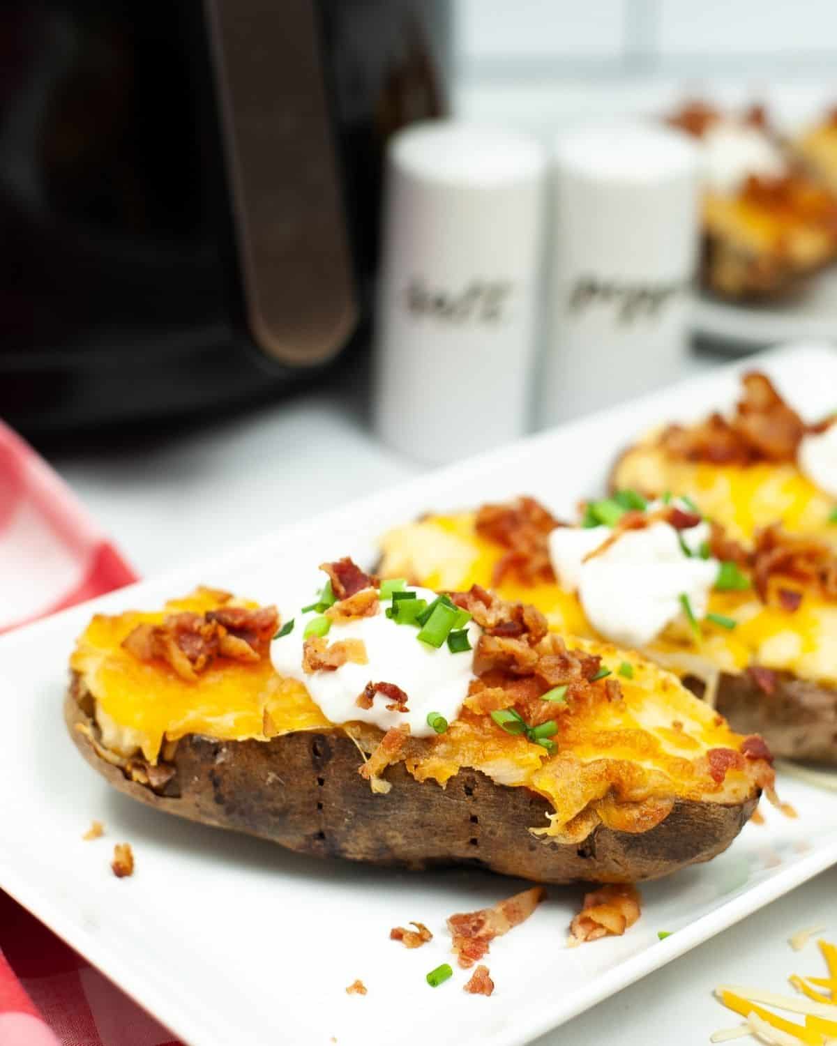 Baked potatoes topped with melted cheddar cheese and crumbled bacon on a plate.