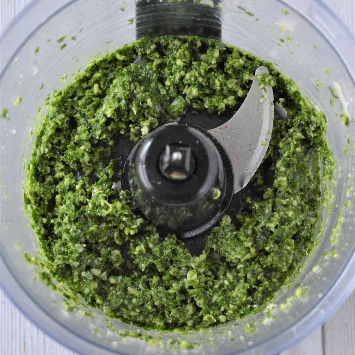 The ingredients for kale pesto in a food processor after they have been blended together.