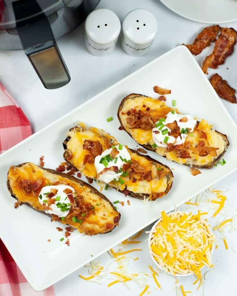 An overhead view of baked potatoes stuffed with cheese and bacon with sour cream.