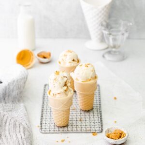 Cheesecake ice cream in a sugar cone on a wire wrack.