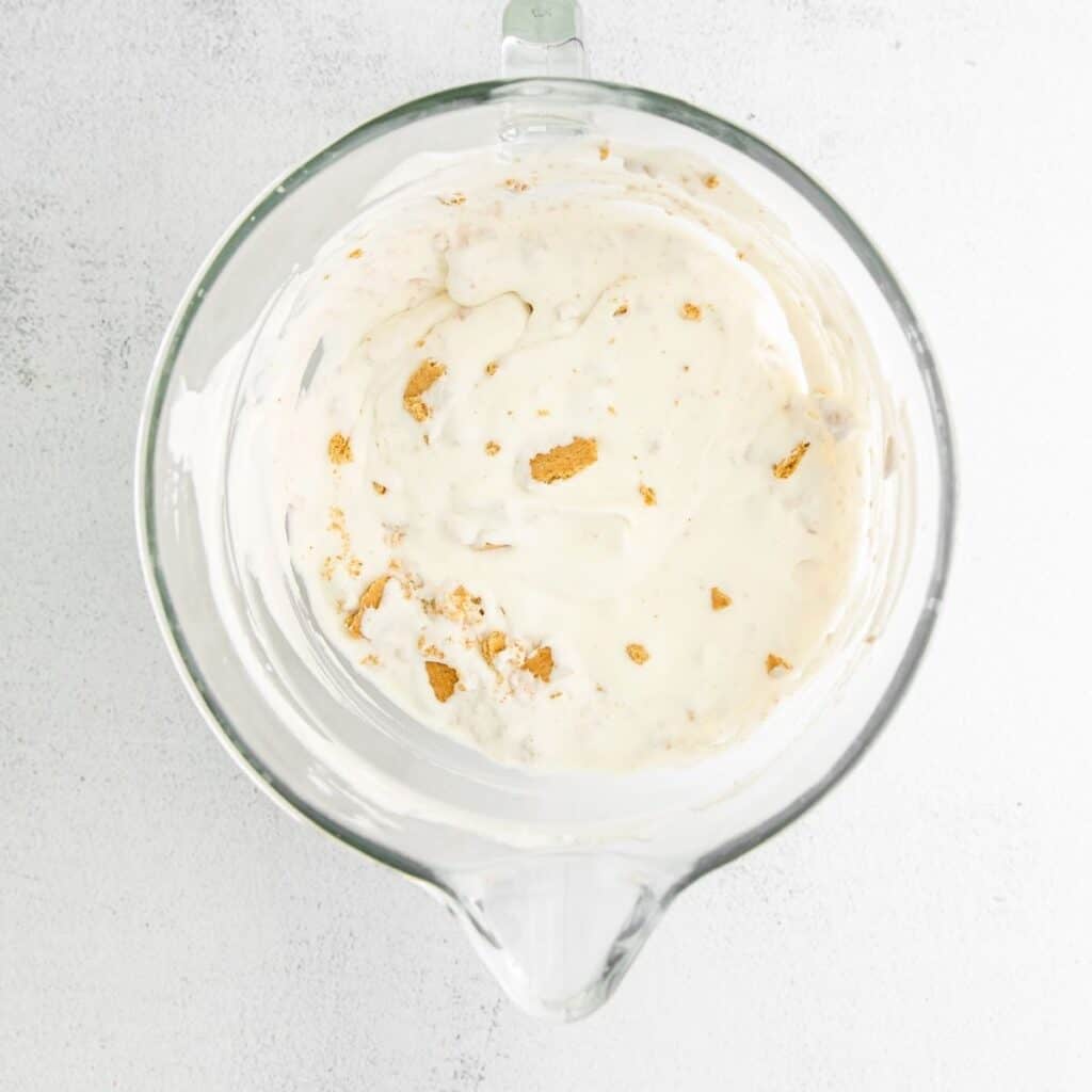 A glass bow with whipped cream and graham crackers in the bowl.