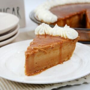 A slice of caramel pie with a whole caramel pie behind it.