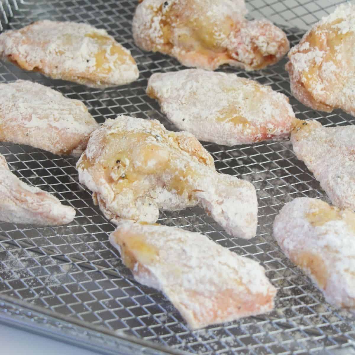 Seasoned chicken wings with lemon pepper wings on the rack of an air fryer. 