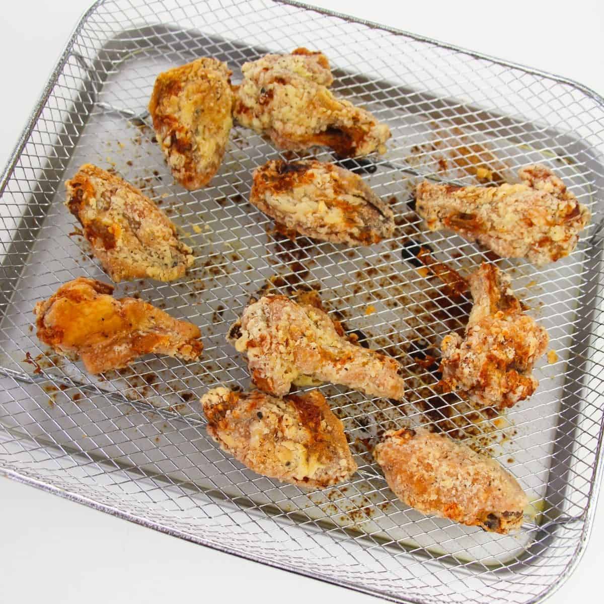 Air fryer lemon pepper wings cooked and on a rack of an air fryer. 