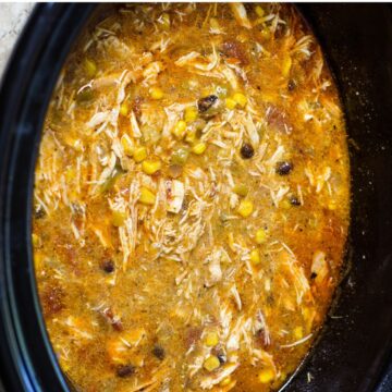 The ingredients for slow cooker chicken enchilada soup that has been cooked and chicken shredded.