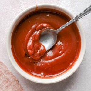 An overhead view of caramel sauce in a bowl with a silver spoon in the sauce.