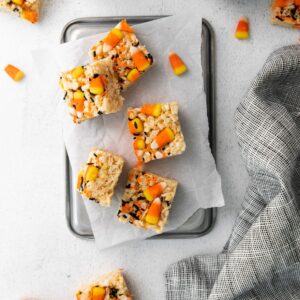 Festive cereal treats decorated for halloween with candy corn sprinkled around the rice treats.